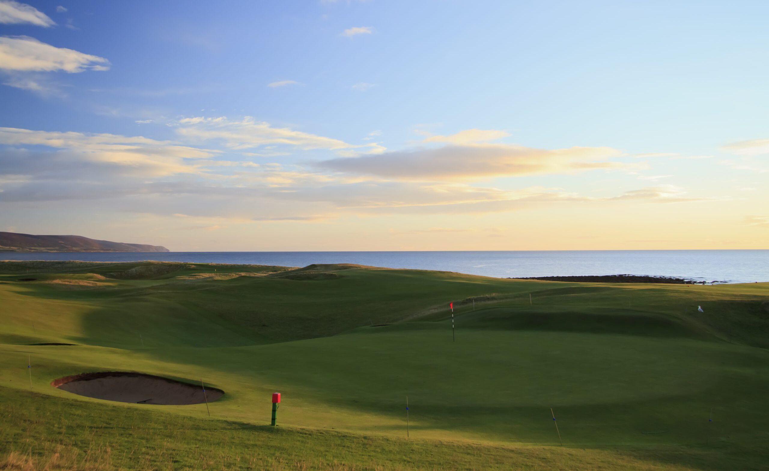Early evening sunlight casting shadows across the fairways at Brora Golf Club, Scotland