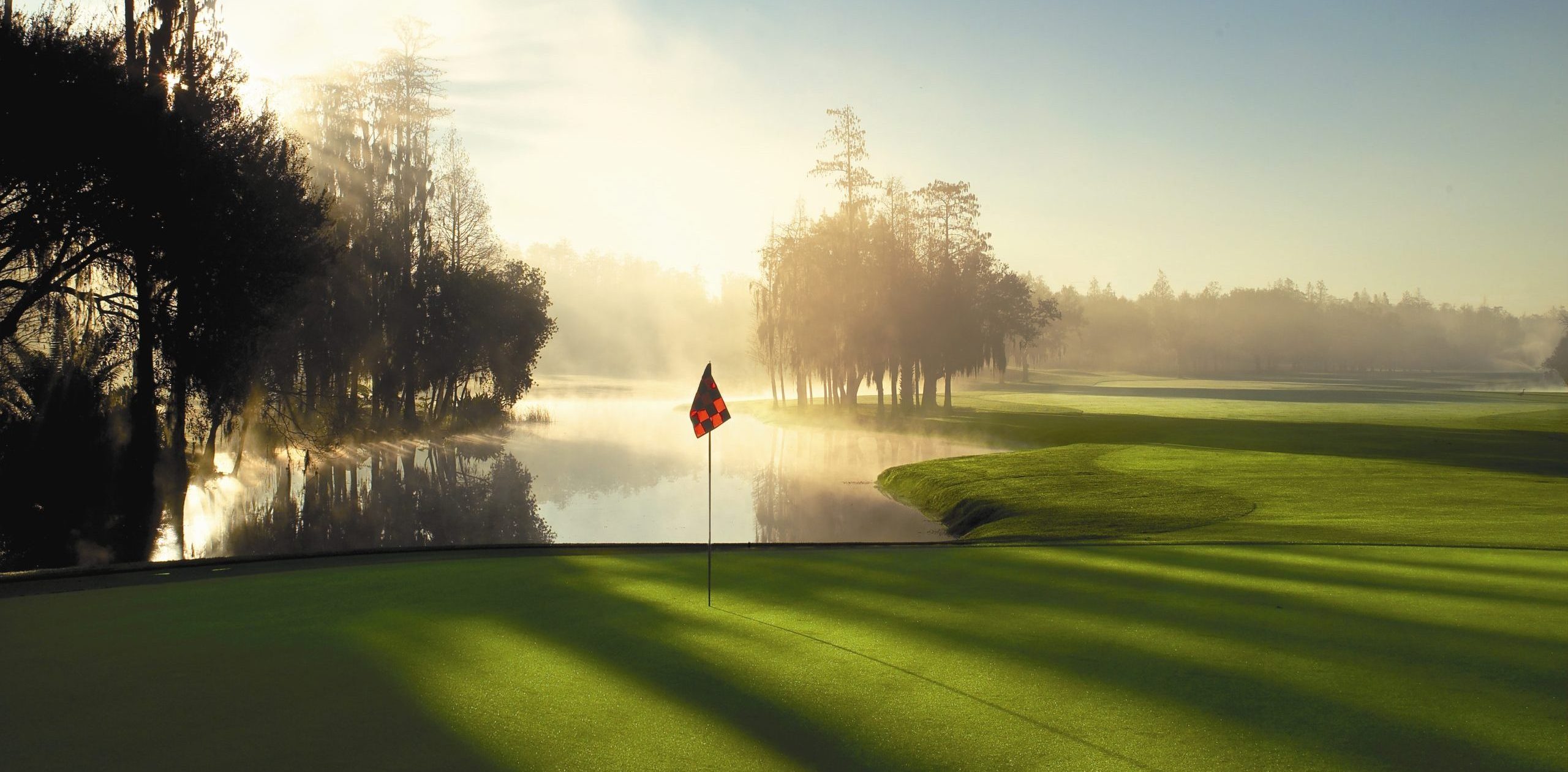 Misty sunrise over a lake and a green at Innisbrook Golf Resort Florida