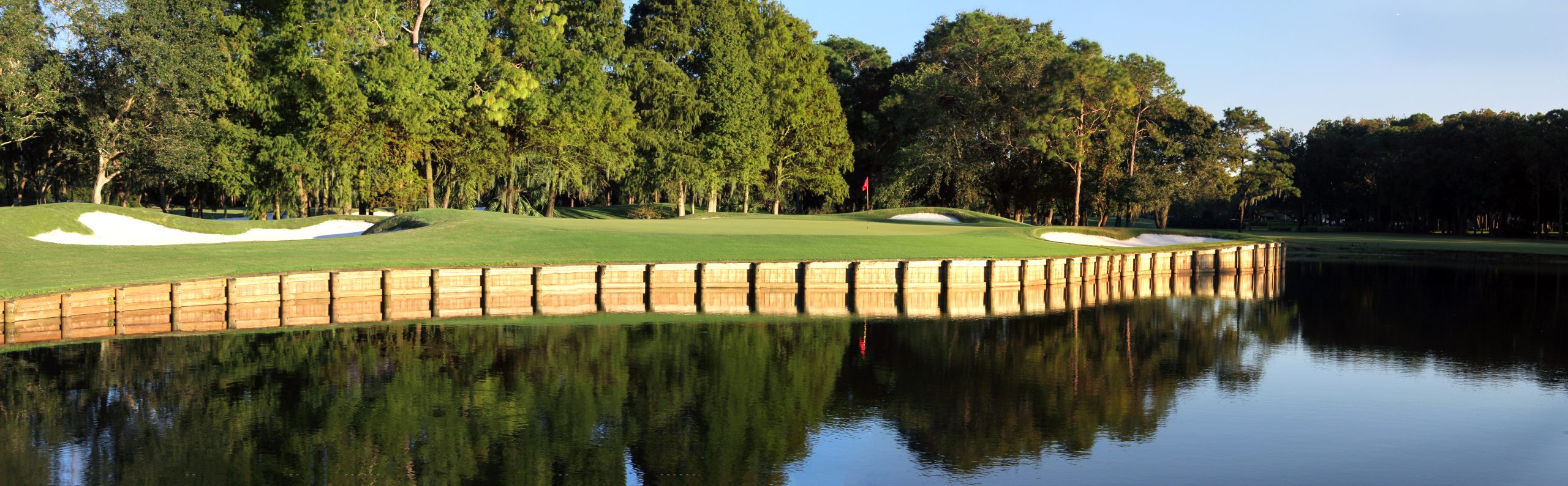 Wooden cladded greens on a lakeside, with bushy tree reflections at Innisbrook Golf Resort, Florida