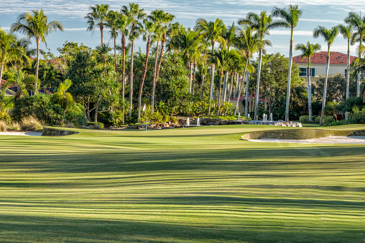 Palm tree lined fairway creating shadows backed by a villa at the Ritz-Carlton Golf Resort Naples