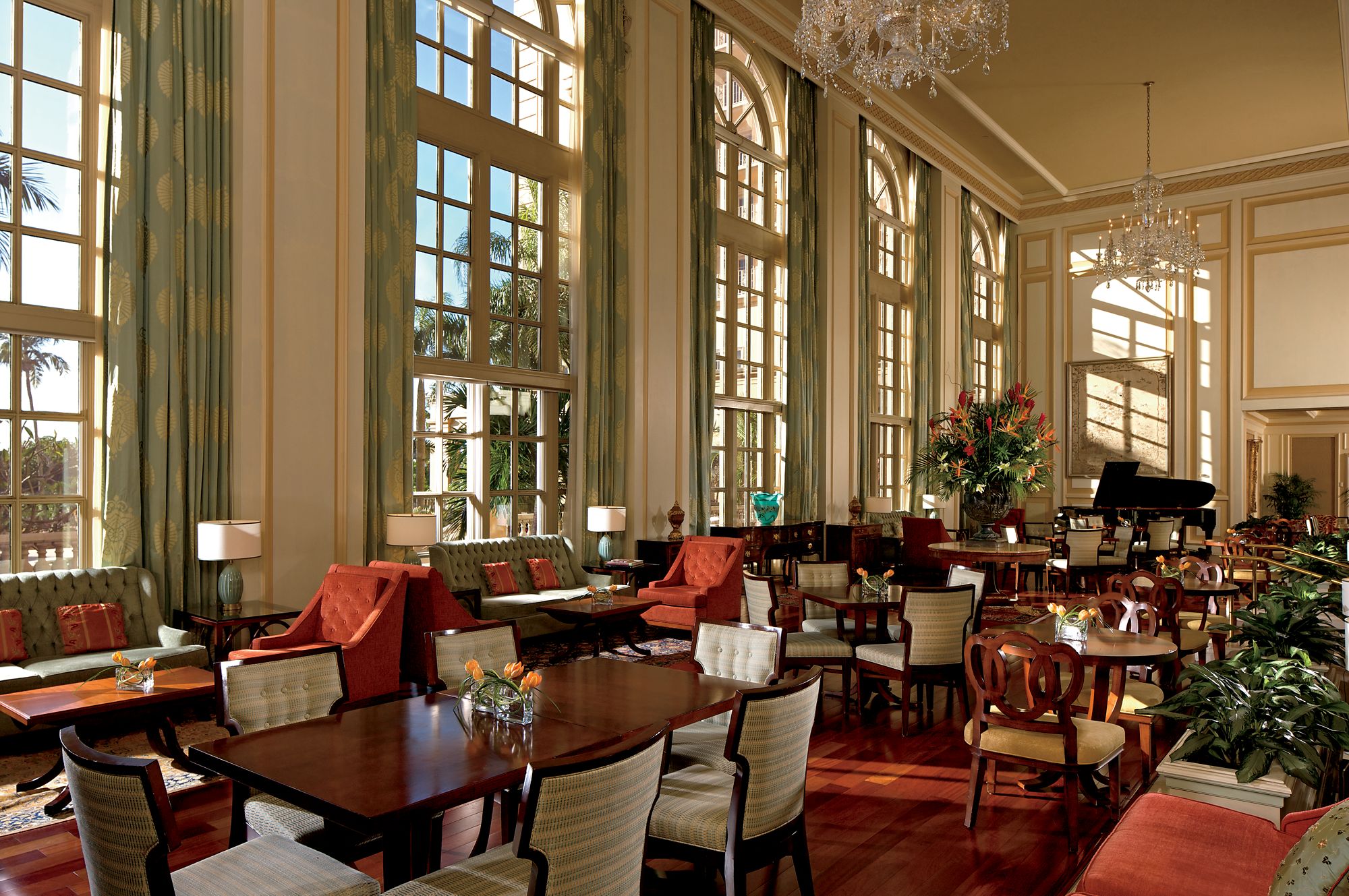 The luxurious dinning room in Ritz Carlton Golf Resort Naples, dark wooden furniture is backed by large arch windows.