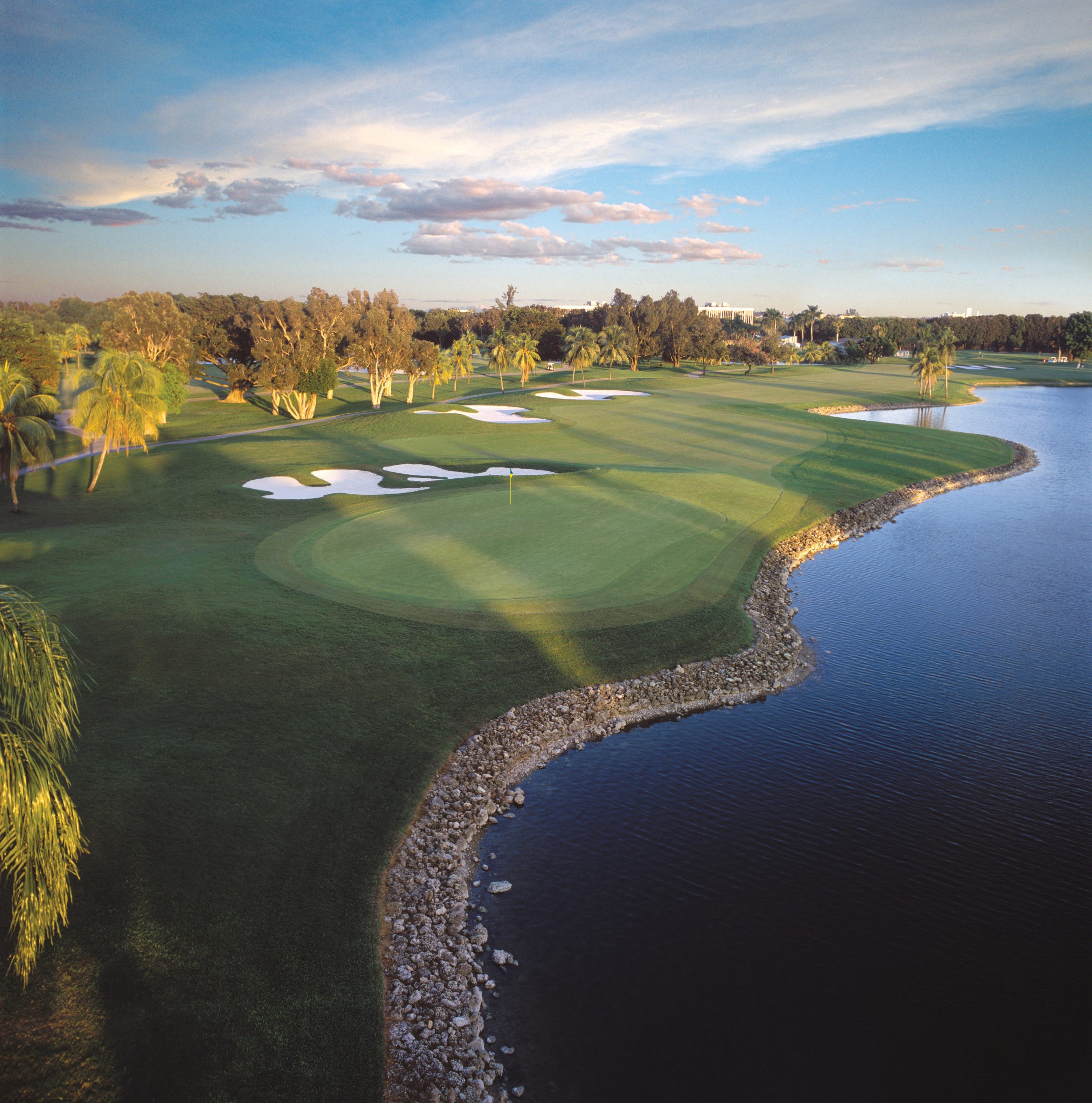 Ariel view of a green alongside a blue lake on a sunny day at Trump National Doral Miami