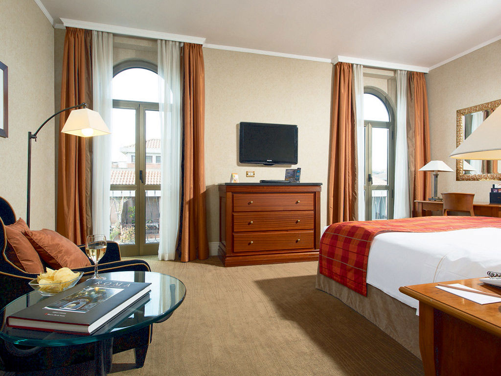 Double bedroom with twin balcony doors and soft furnishings at Hotel Dei Melini