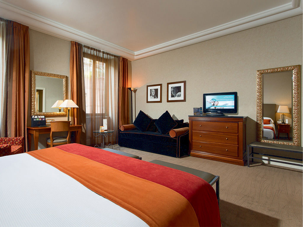 Double room at Hotel Dei Melini, with dark wooden furnishings and orange and red fabrics