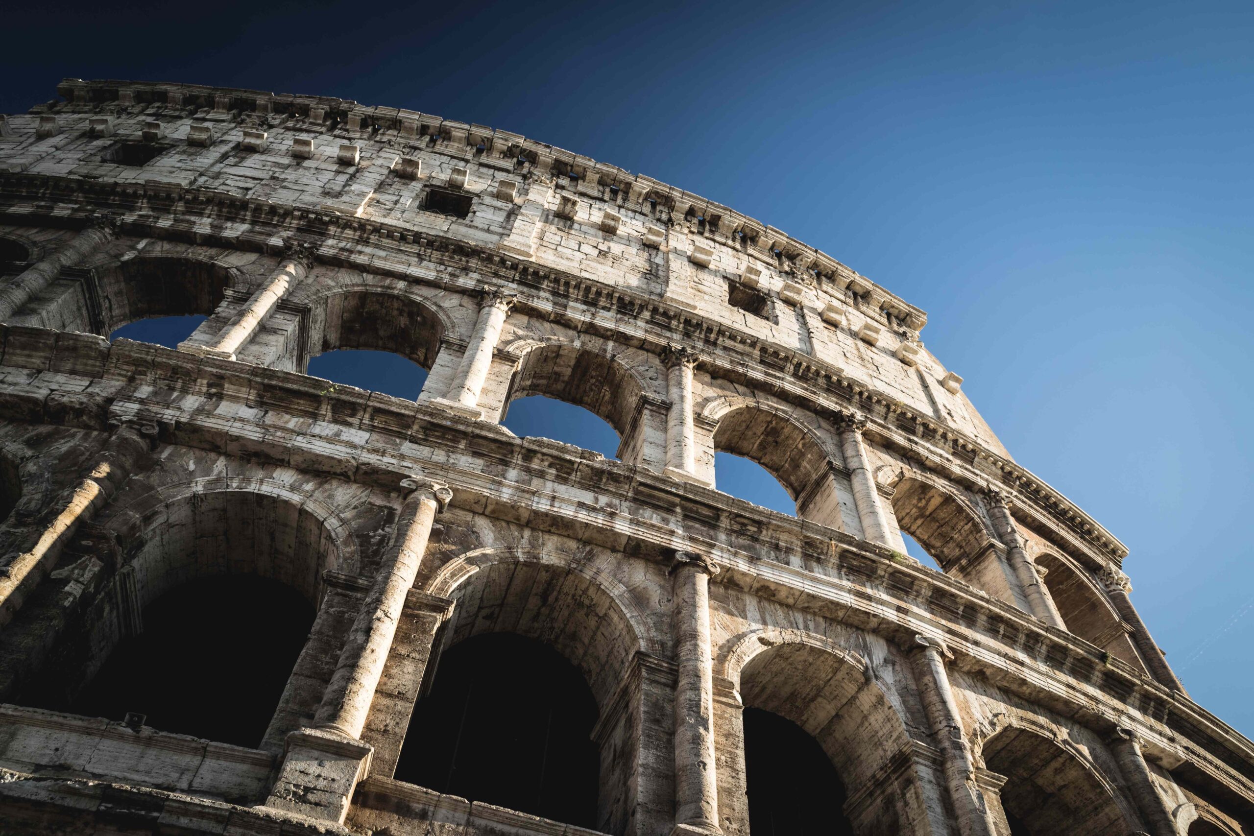 A towering angle of the Colosseum, Rome against a blue sky