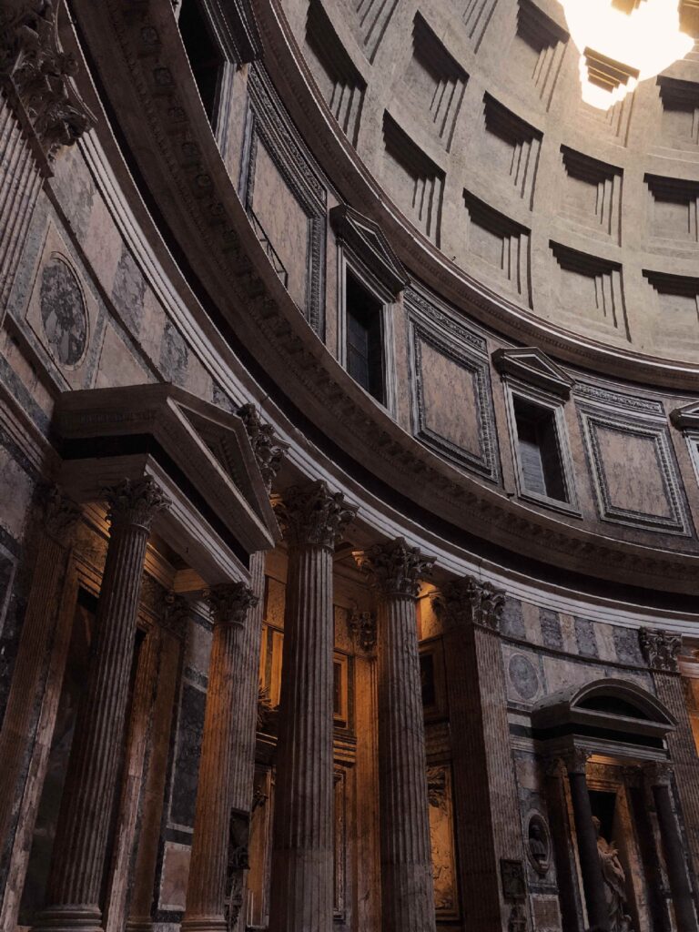 Sunlight coming in through the dome roof of the Pantheon, casting shadows of the ornate interior
